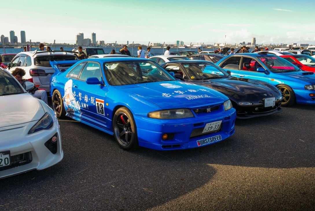 Illustration of iconic JDM cars like the Nissan Skyline, Toyota Supra, and Mazda RX-7 with a beginner-friendly guide headline.