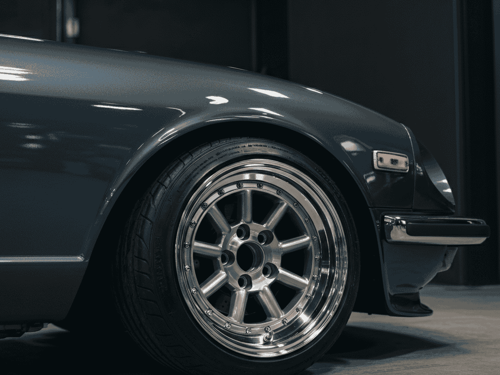 Vintage JDM wheels on a classic sports car parked in a showroom with a polished finish.
