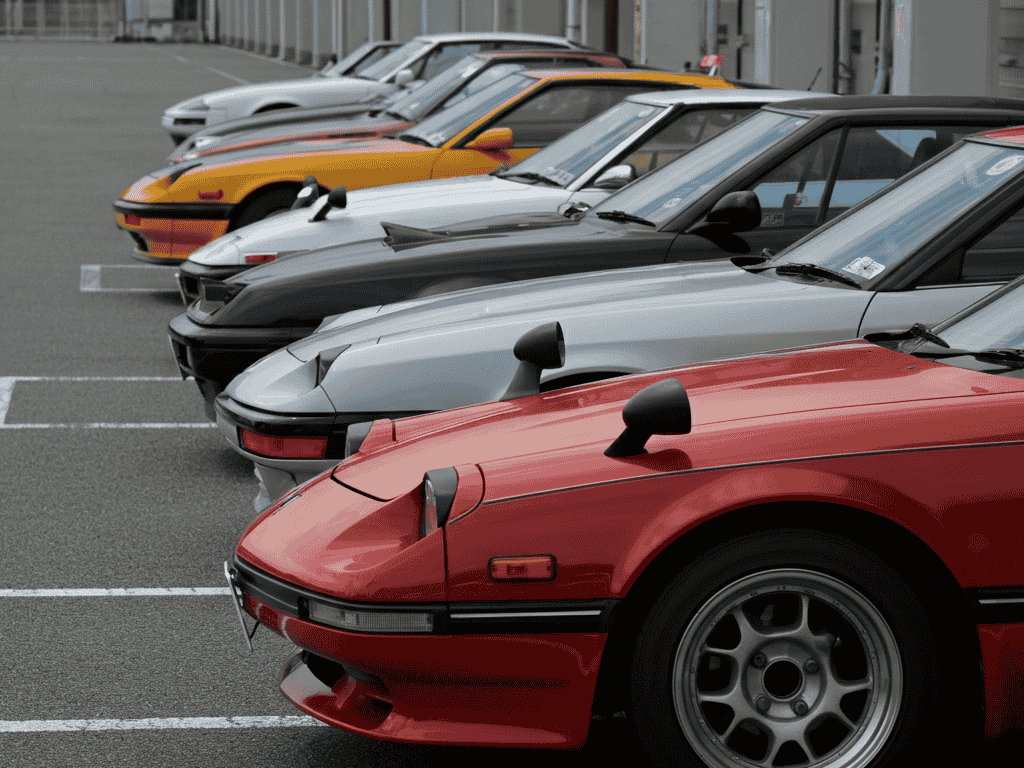 Lineup of iconic Japanese race cars including Toyota Supra A80, Mazda RX-7 FD, Honda NSX, and Datsun 240Z.